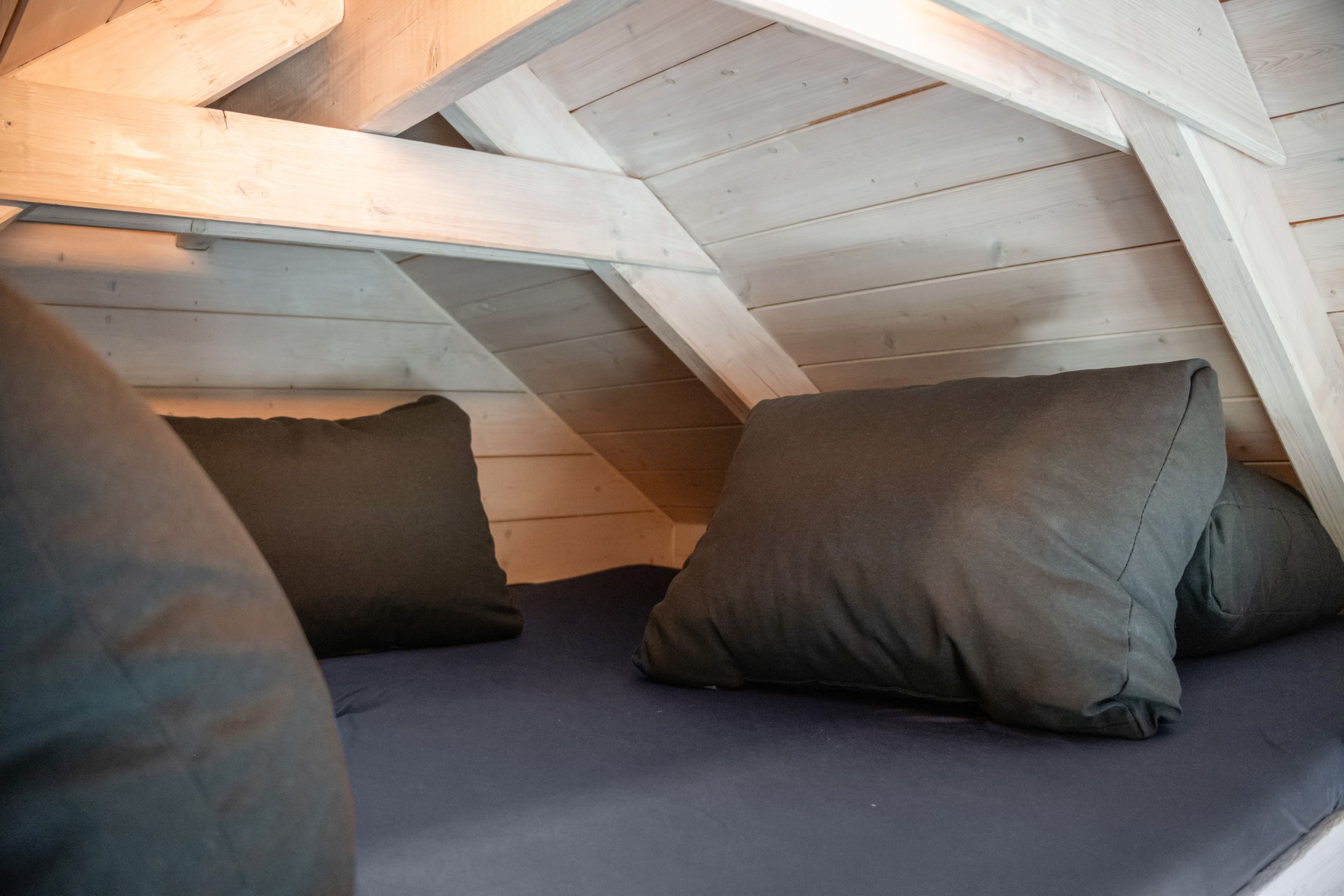 Une chambre mansardée avec des plafonds inclinés et des poutres en bois.