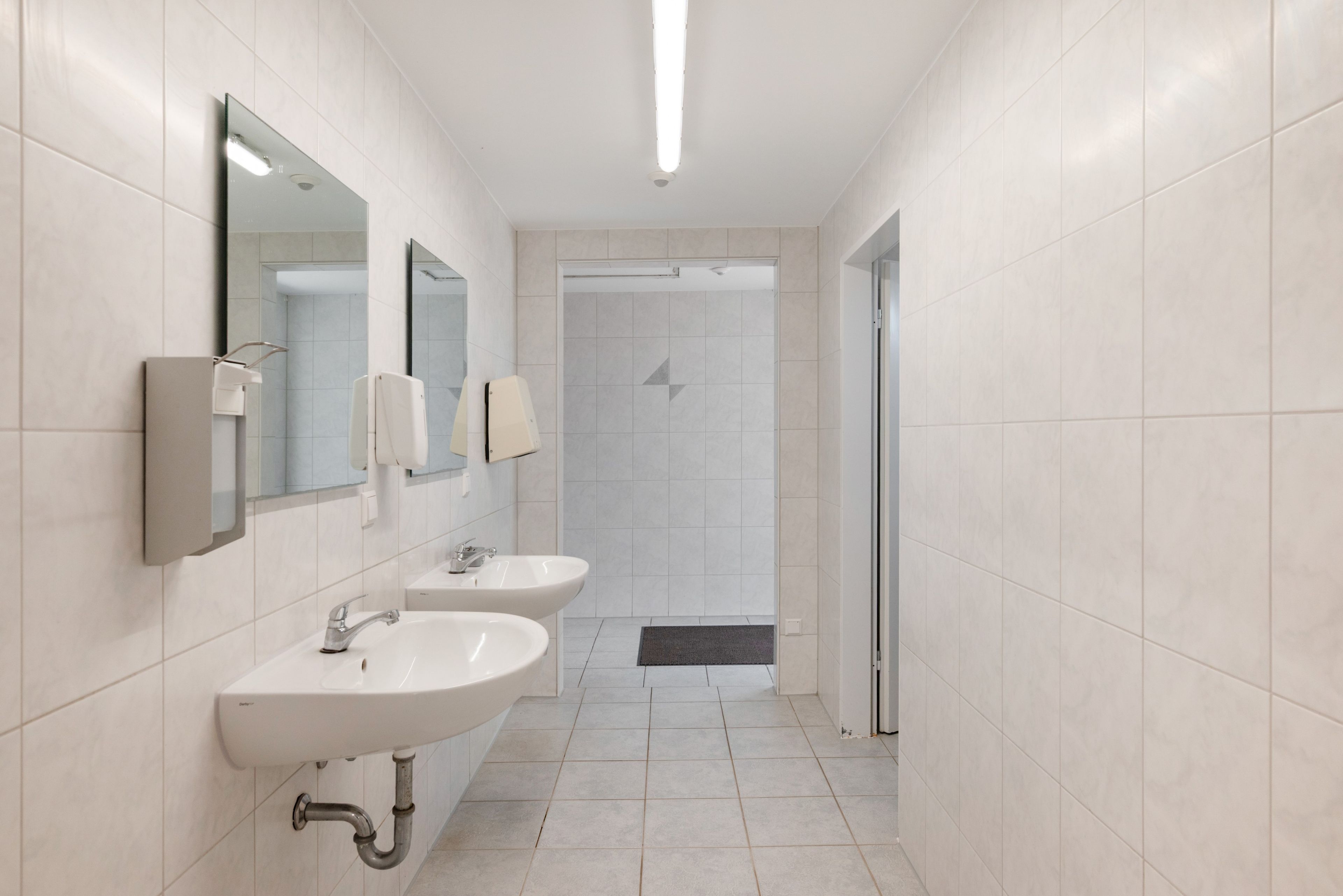 Une salle de bain moderne avec deux lavabos, un miroir et un espace douche.