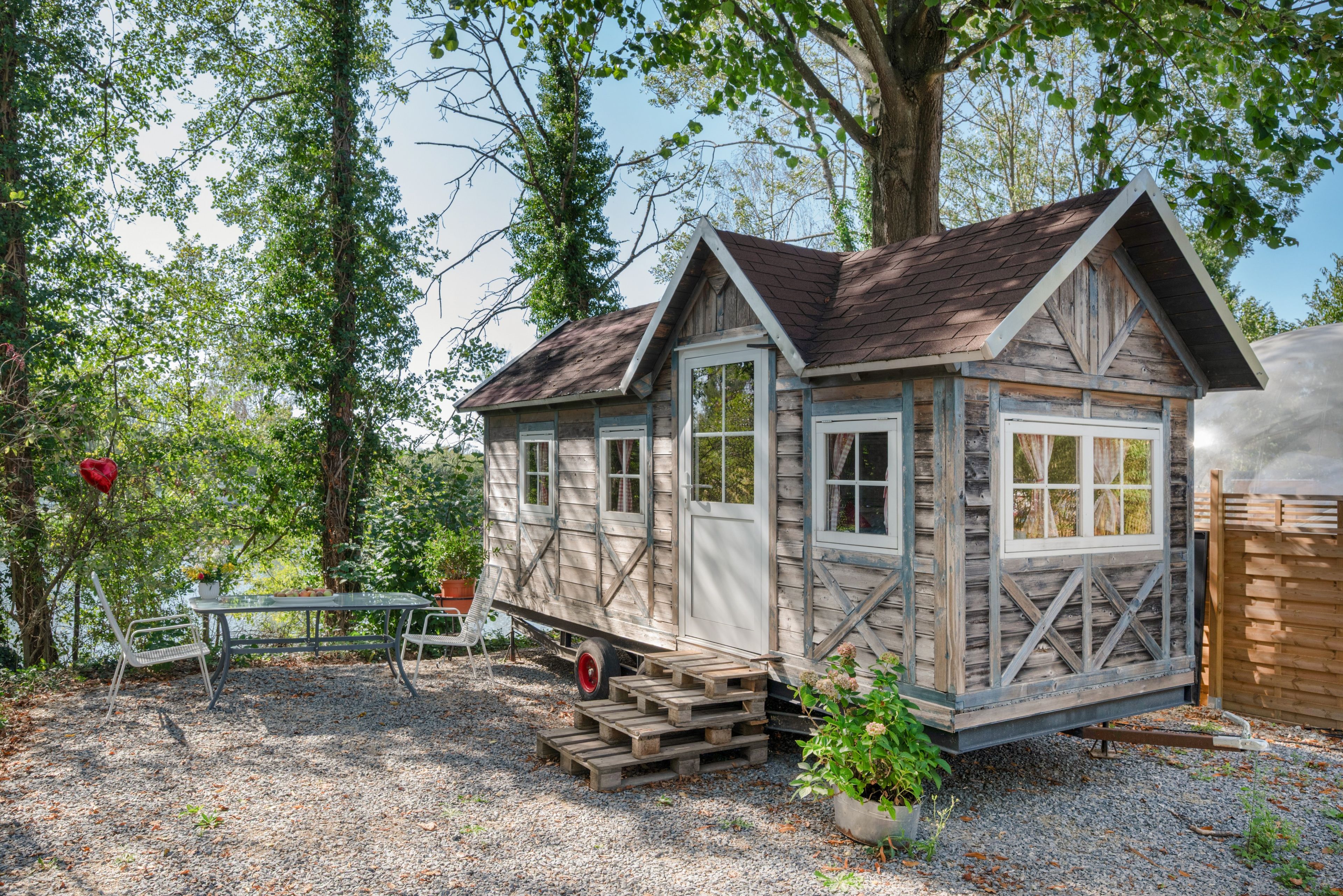 Une cabane en bois avec une véranda, une table et des chaises à l’extérieur.