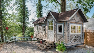 Une cabane en bois avec une véranda, une table et des chaises à l’extérieur.