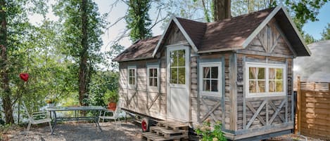 A wooden cabin with a porch, a table, and chairs outside.
