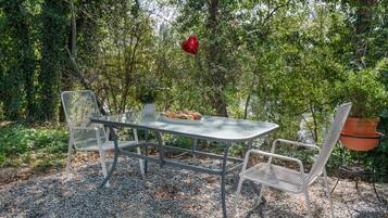 An outdoor dining area with a table and chairs, surrounded by greenery.
