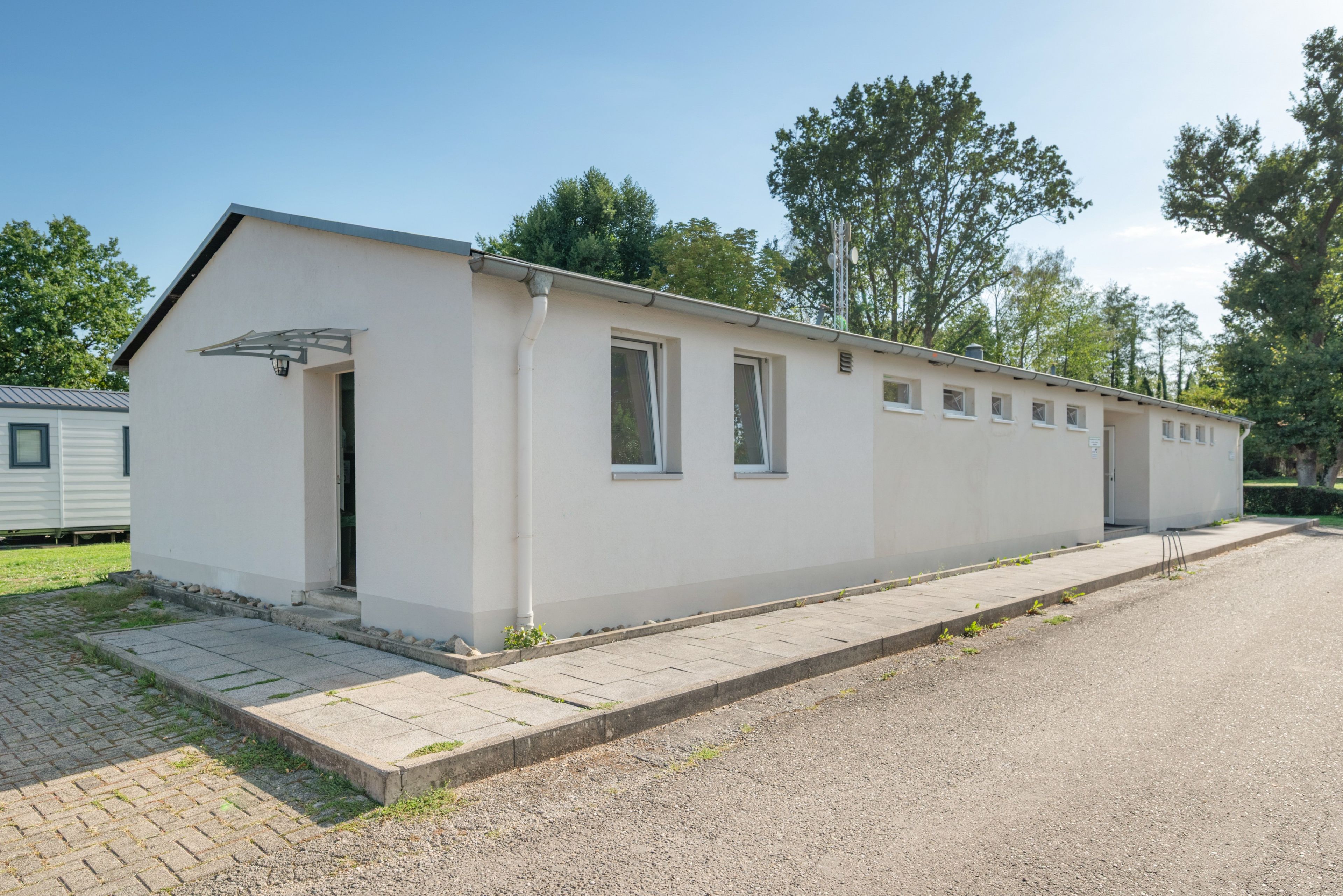 Ein eingeschossiges Gebäude mit Flachdach, Tür und mehreren Fenstern.