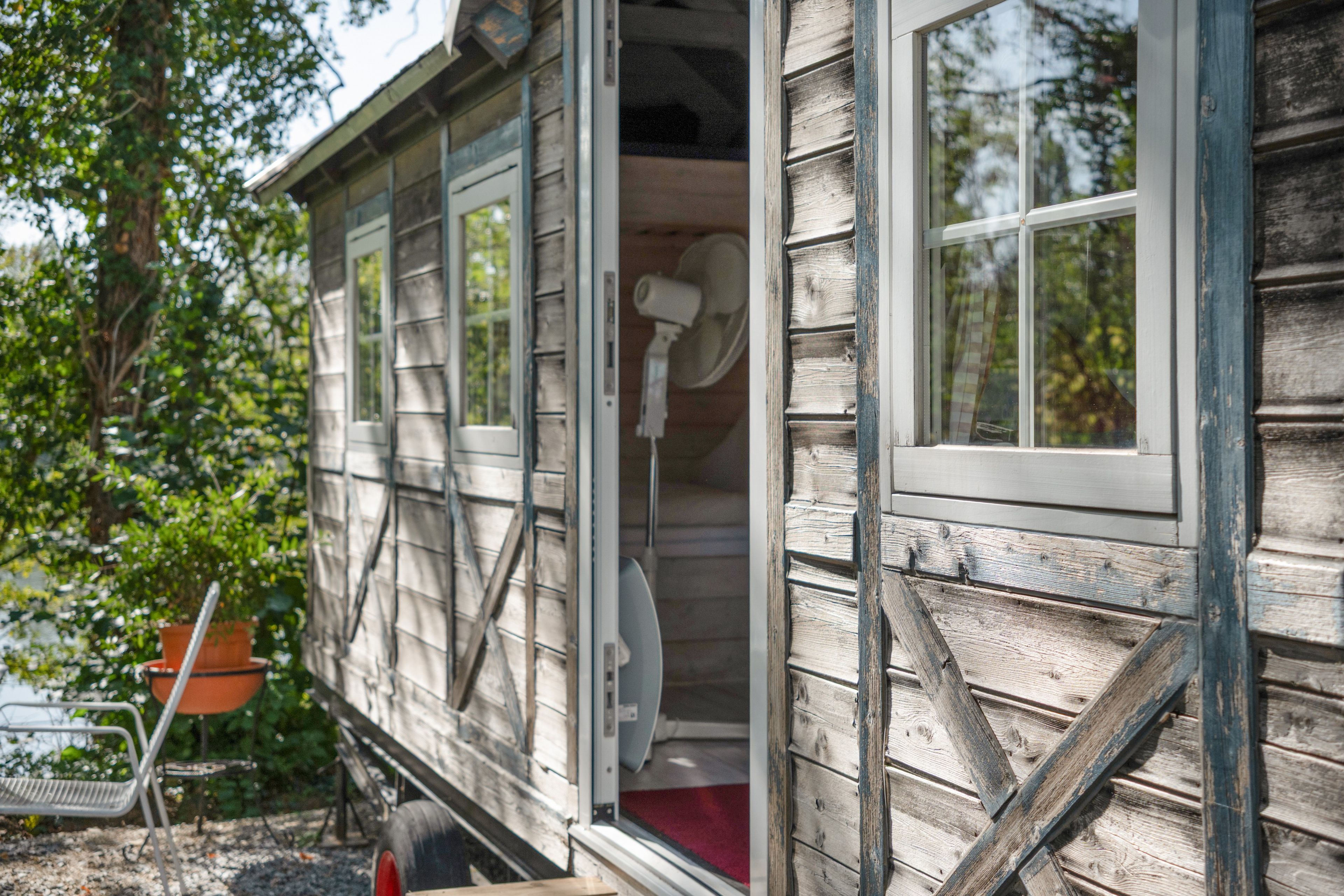 Een houten huis met een openstaande deur, waar een rood interieur zichtbaar is.