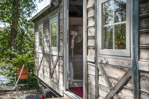 A wooden house with a door open, revealing a red interior.
