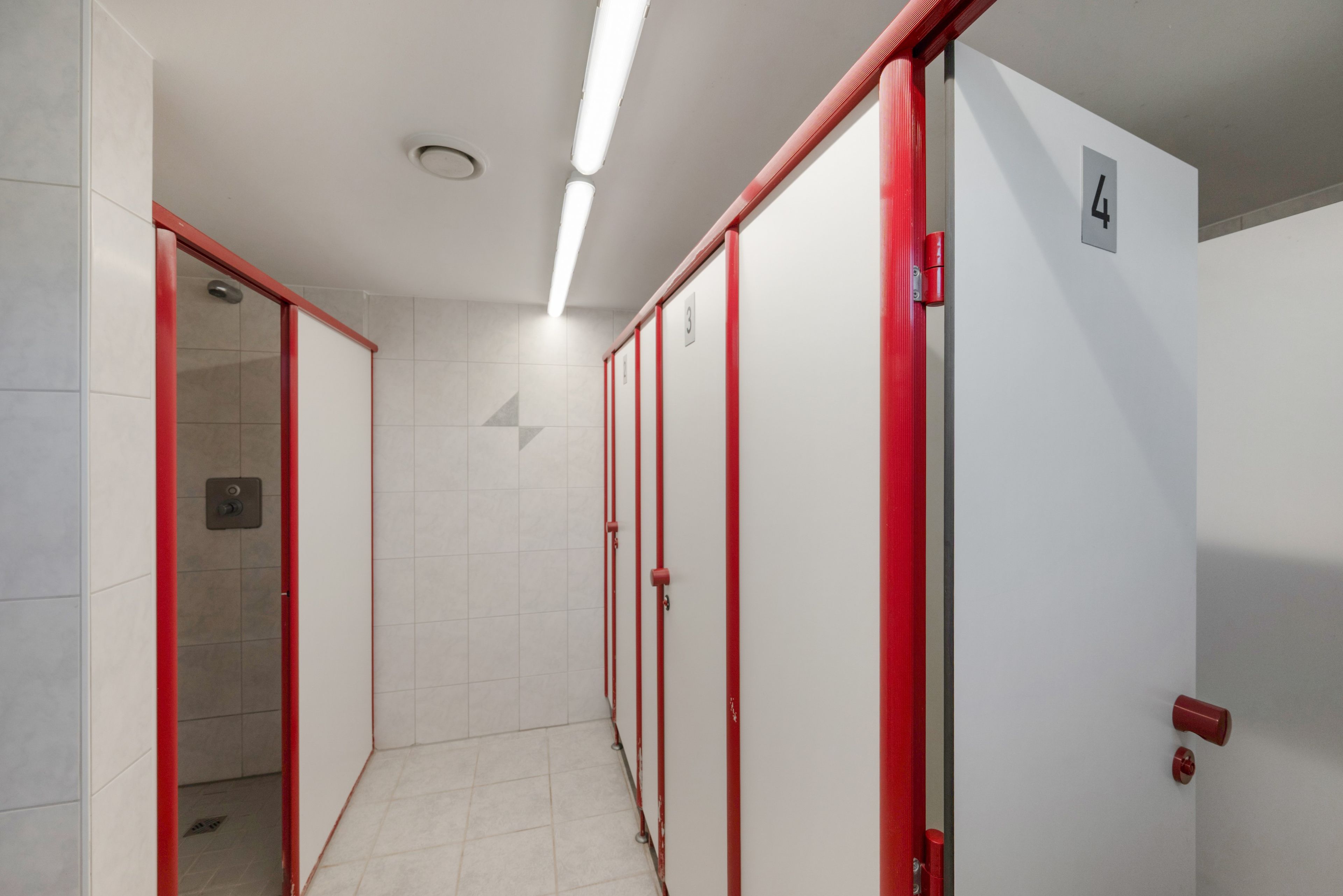 A hallway with lockers, a door marked with the number 4, and a tiled floor.