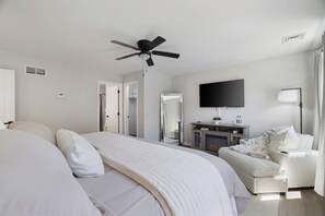 Et hotelværelse med seng, siddeområde med stol, fjernsyn og pejs.