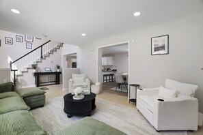 A spacious living area with a staircase, a dining area, and a kitchen. - Pocono Oasis | Hot Tub • Game Room • Fenced Yard (Long Pond)