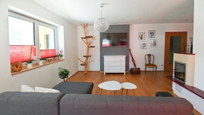 En moderne stue med sofa, sofabord, pejs og et spiseområde med stol og bord.