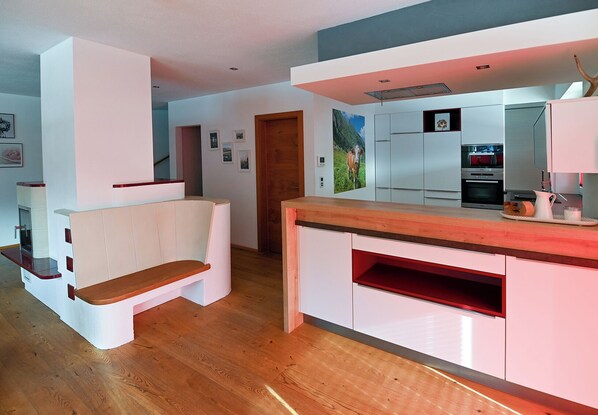 A modern kitchen with white cabinetry, a wooden countertop, and a built-in oven.