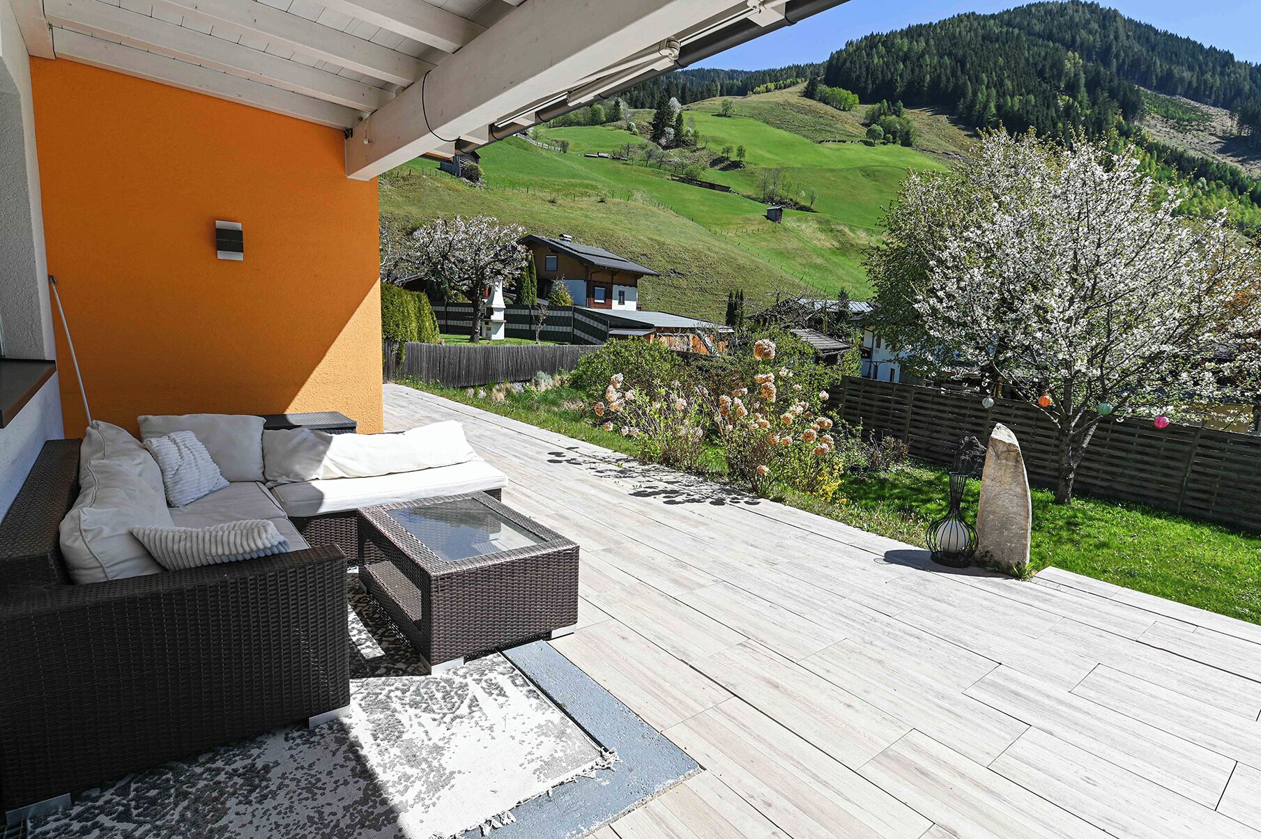 Ein überdachter Außenbereich mit Korbmöbeln und Blick auf eine grüne Landschaft.