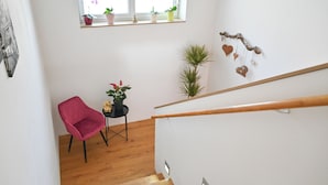En trappe med gelænder af træ, en rød stol og plantekasser på et repos.
