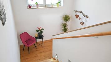 Eine Treppe mit Holzgeländer, einem roten Stuhl und Blumentöpfen auf einem Zwischenpodest.