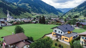 A village with a church, houses, and a large green field. - Chalet Creatina by we rent (Rauris)