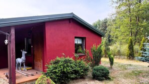 A red building with a porch, a statue, and a small garden.