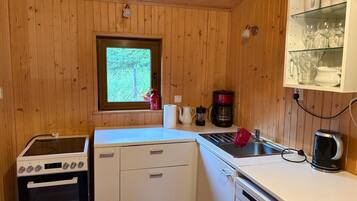 Uma cozinha compacta com fogão, forno, pia e uma janela com vista para o verde.