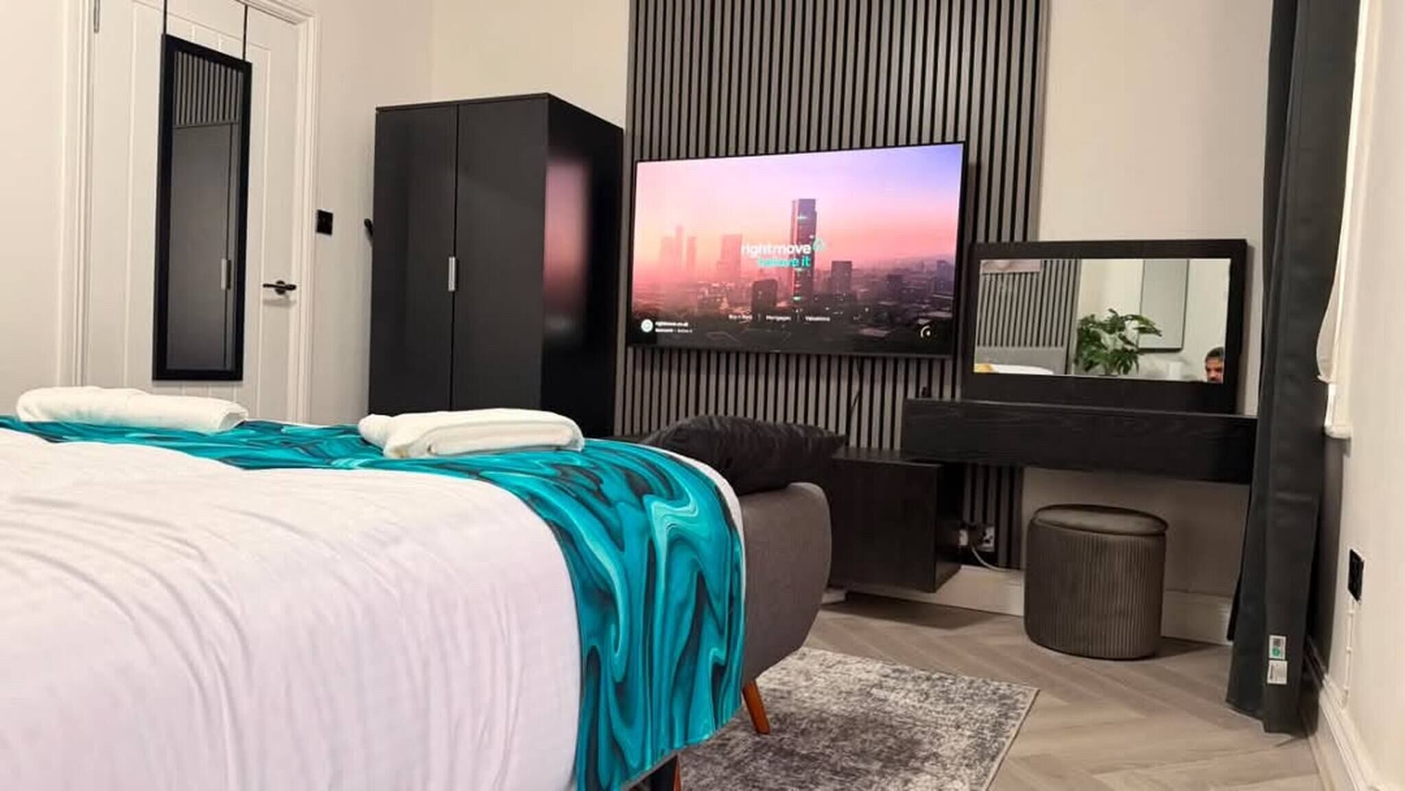Une chambre à coucher moderne, équipée d’un lit, d’une armoire, d’un téléviseur et d’un miroir.