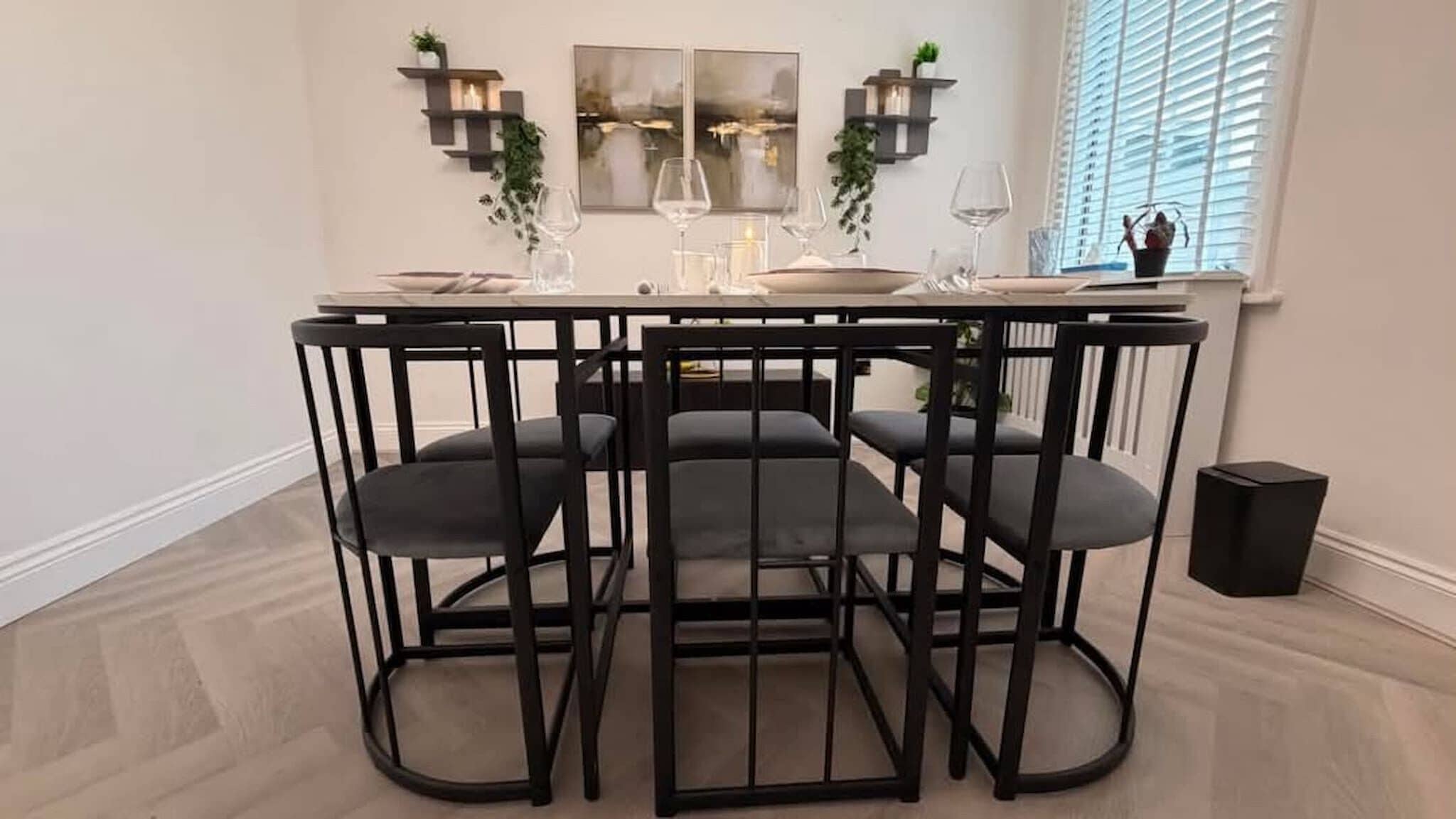 A dining area with a round table, four chairs, and a window with blinds.