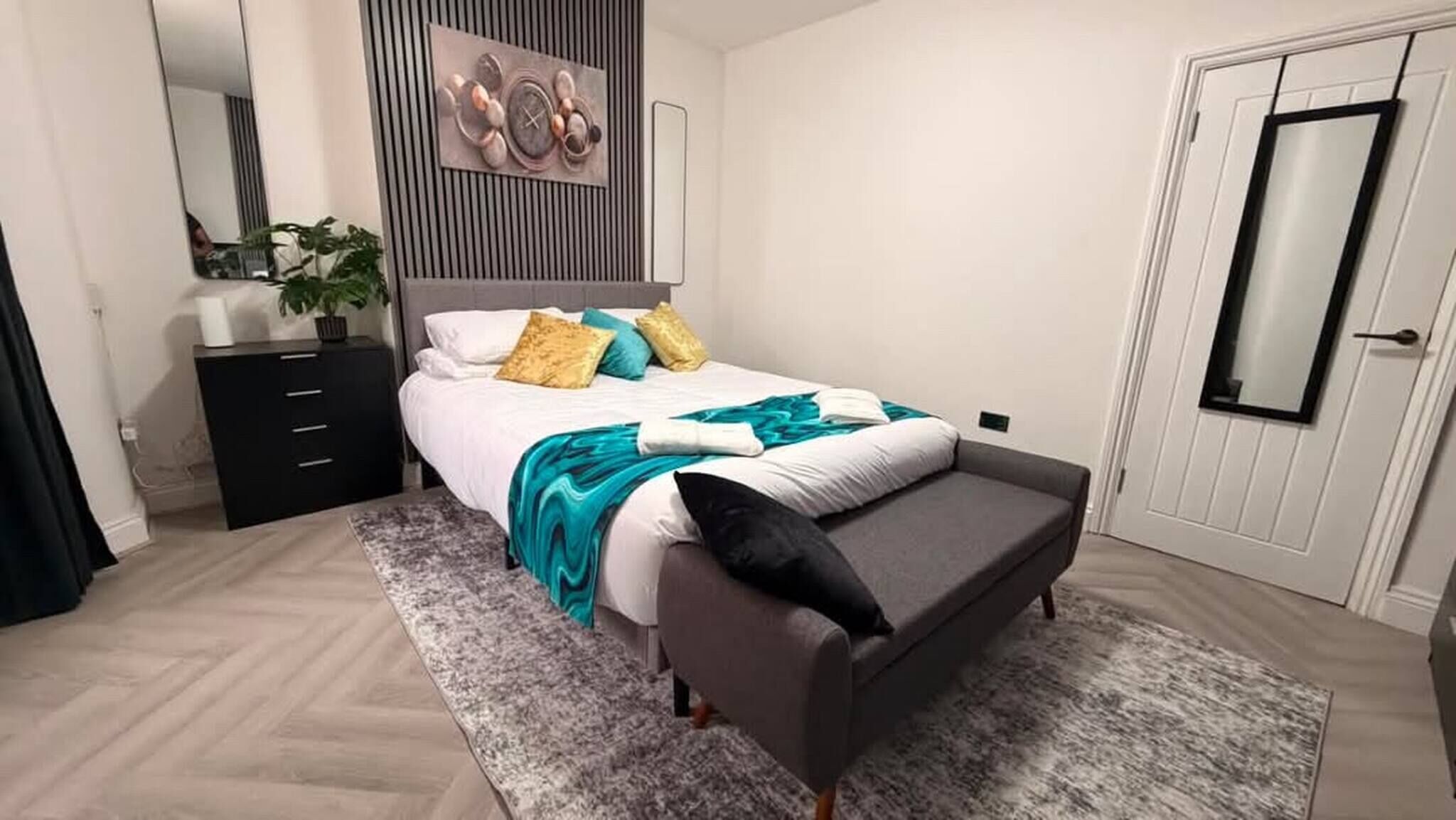 Una habitación de hotel con cama, mesita de noche y espejo.