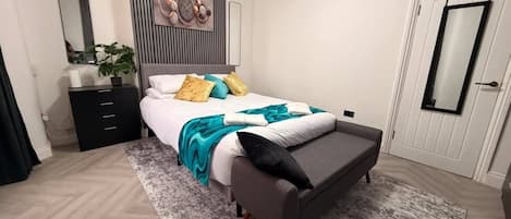 Una habitación de hotel con cama, mesita de noche y espejo.