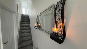 Eine Treppe mit an der Wand befestigtem Spiegel und Kerzenhaltern.