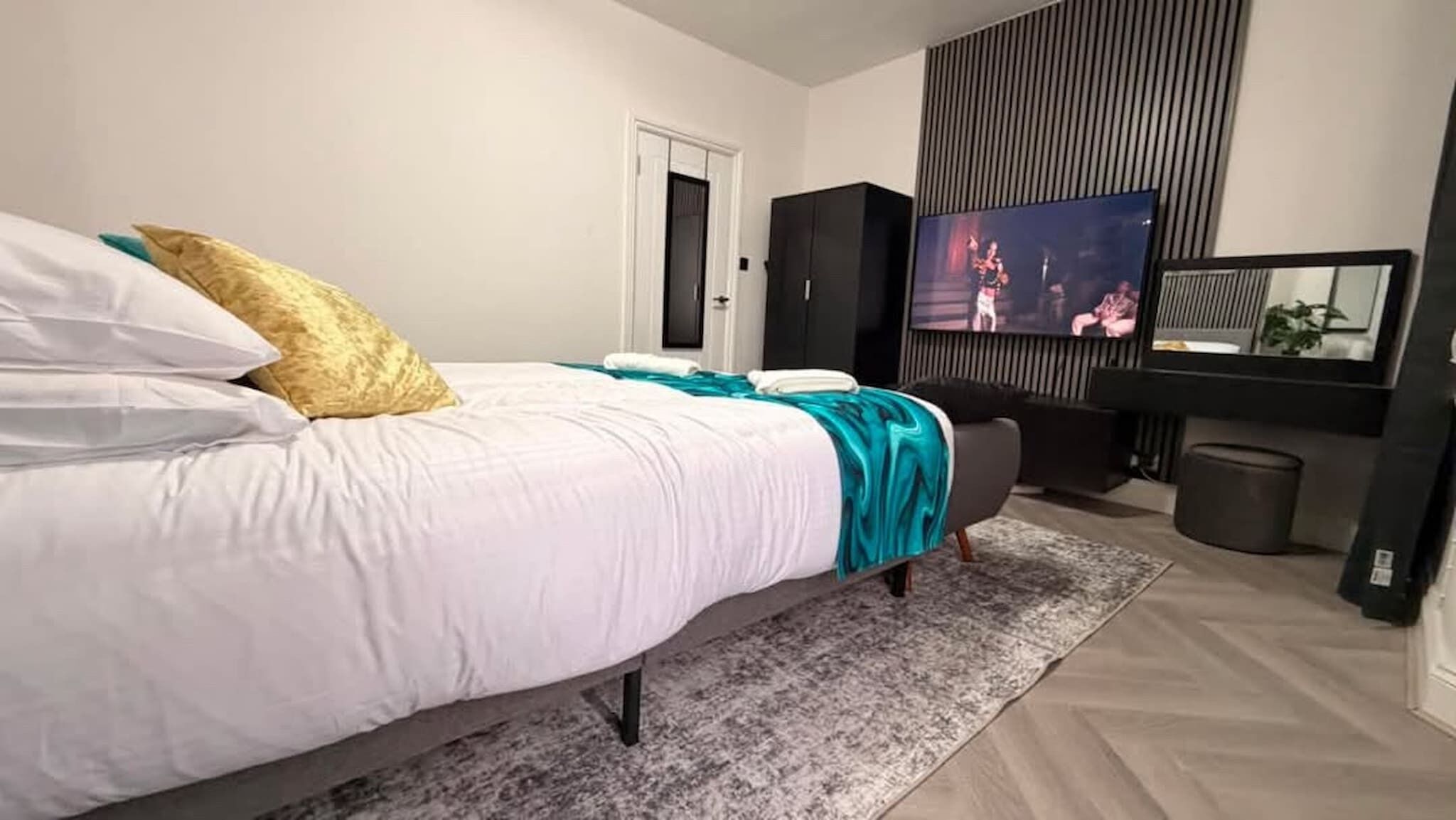 Un dormitorio moderno con cama, televisión y un armario oscuro.