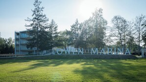 Un letrero con el texto 'LOWEN MARINA' en una zona ajardinada con césped y árboles.