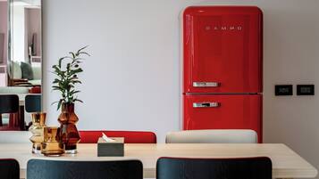 Un comedor con un refrigerador rojo, un florero y una caja de pañuelos sobre la mesa.