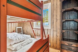 Une pièce en bois avec un lit superposé, une fenêtre donnant sur un beau paysage et une armoire en bois.