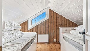 Un dormitorio en ático pequeño con dos camas, una ventana y paredes de madera.