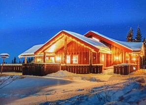 Eine Holzhütte mit verschneitem Dach und einer Veranda, umgeben von Schnee.