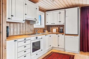 A kitchen with white cabinets, a wooden countertop, a built-in oven, and a refrigerator.