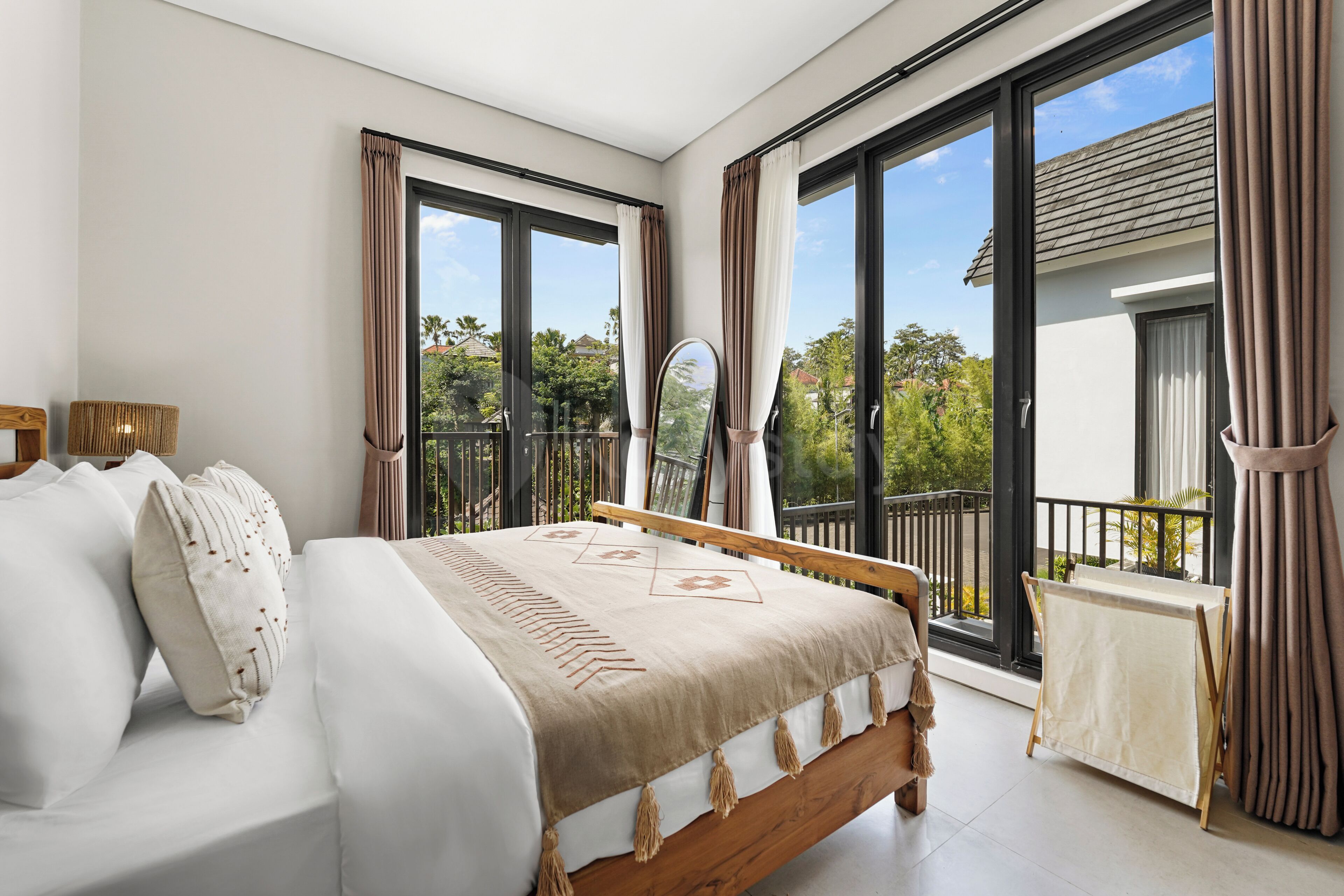 A bedroom with a bed, a small table, and a view of the outdoors.