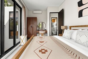 A hotel room with a bed, a desk, a chair, a mirror, and a window.