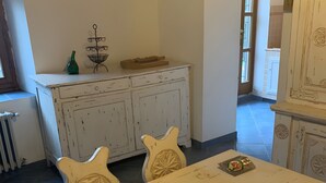 A dining area with a white table, two chairs, and a cabinet with a metal rack on top. - Country House 'Le Mulina' with Wi-Fi (Barberino di Mugello)