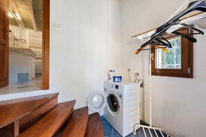 Une buanderie équipée d’un lave-linge, d’un étendoir et d’un banc.
