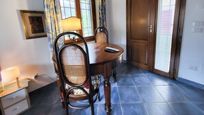 A dining area with a wooden table, two chairs, a lamp, and a door with a window. - Country House 'Le Mulina' with Wi-Fi (Barberino di Mugello)