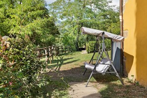 A garden with a swing set and a yellow wall. - Country House 'Le Mulina' with Wi-Fi (Barberino di Mugello)