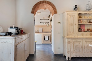 A kitchen with a brick archway, white cabinets, and a tiled floor. - Country House 'Le Mulina' with Wi-Fi (Barberino di Mugello)