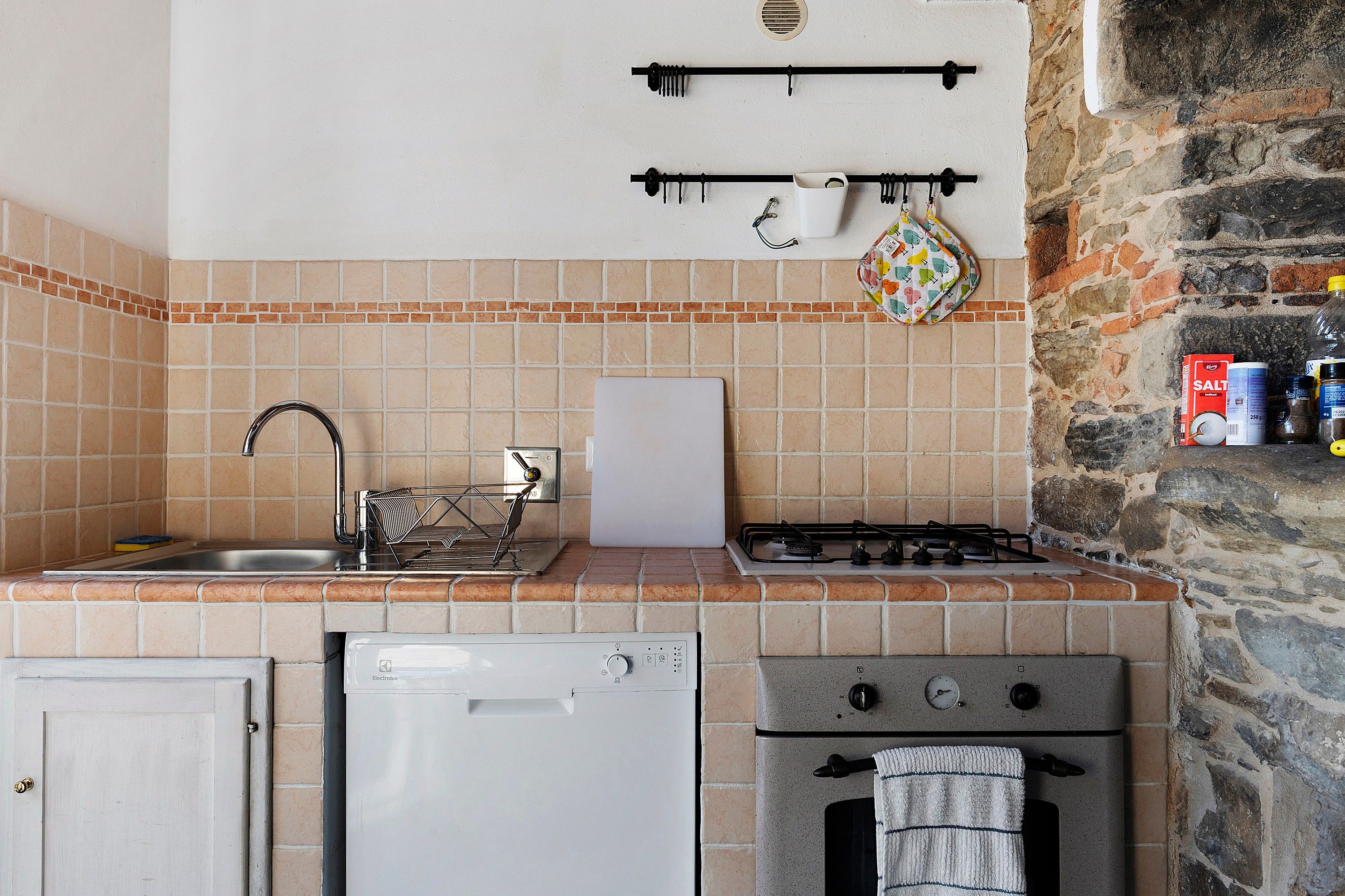 Una cocina funcional con lavavajillas, estufa a gas y un colgador para ollas.