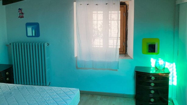 A bedroom with a bed, dresser, radiator, and a window with curtains. - Country House 'Le Mulina' with Wi-Fi (Barberino di Mugello)