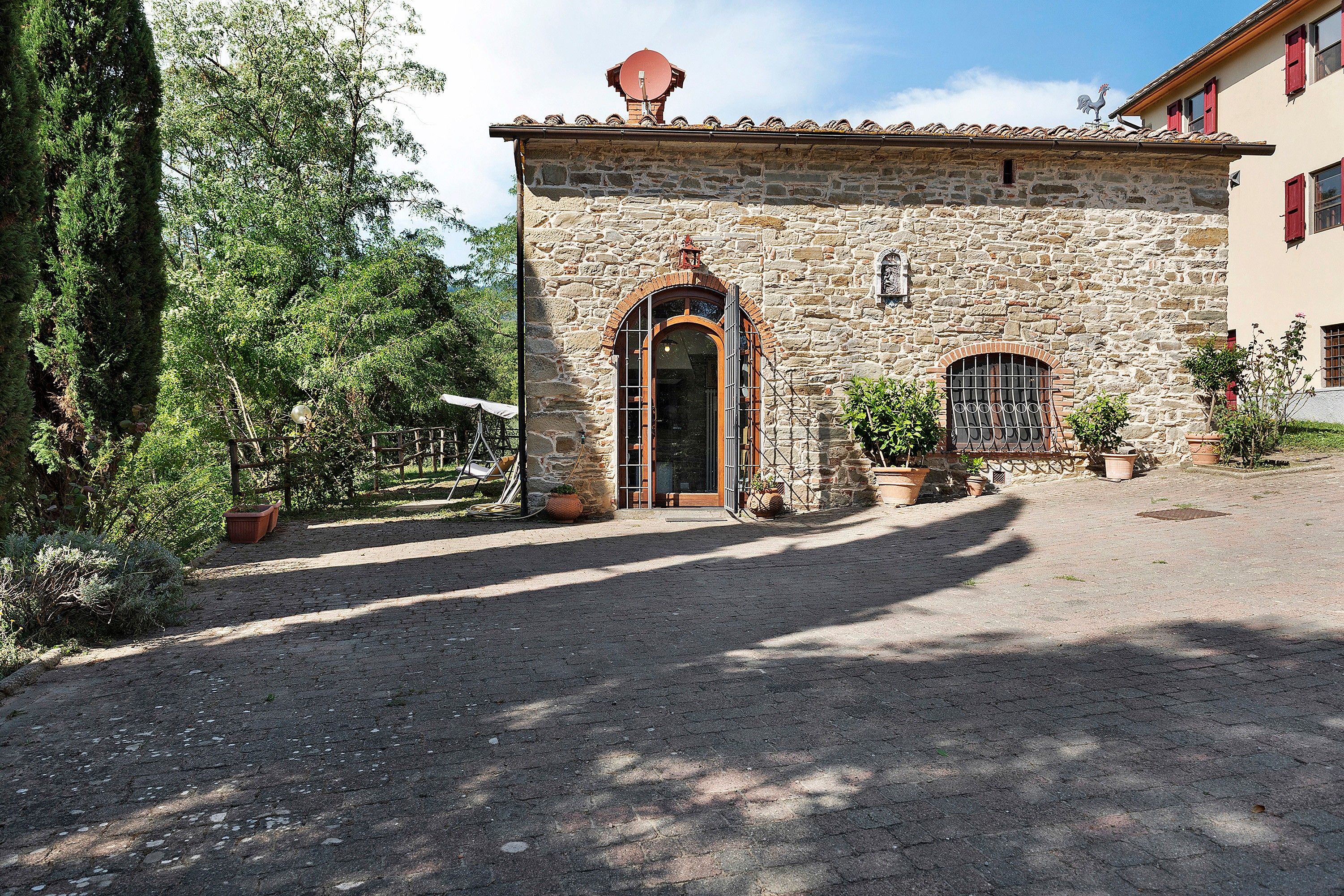 A stone building with a tiled roof, a central arched doorway, and a small window with bars.