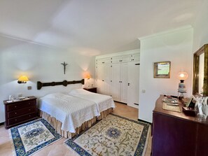 A bedroom with two beds, a wardrobe, a nightstand, a lamp, and a mirror. - Vilamoura Vintage Villa by Homing (Loulé)