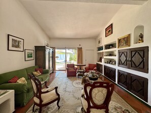 A living room with a green sofa, two wooden chairs, a coffee table, and a patterned rug. - VILAMOURA VINTAGE VILLA WITH POOL by HOMING (Vilamoura)