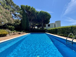 A swimming pool with clear blue water, surrounded by greenery and a white building. - VILAMOURA VINTAGE VILLA WITH POOL by HOMING (Vilamoura)