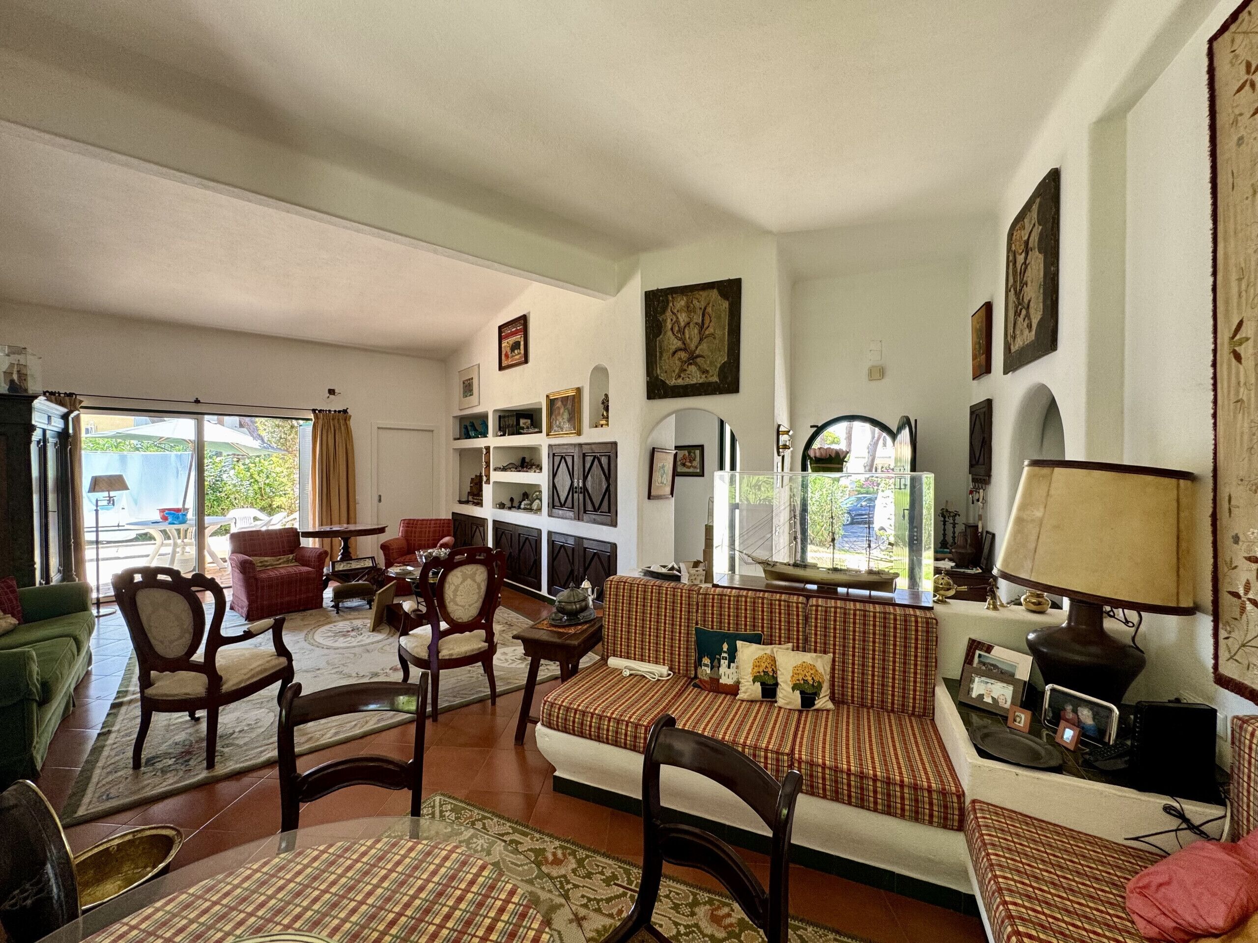 A spacious living room with a sofa set, chairs, a dining table, and a bookshelf.