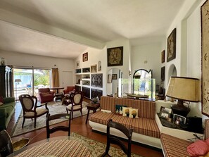 A spacious living room with a sofa set, chairs, a dining table, and a bookshelf. - VILAMOURA VINTAGE VILLA WITH POOL by HOMING (Vilamoura)