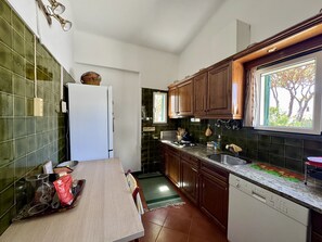 A compact kitchen with a refrigerator, a sink, and wooden cabinets. - VILAMOURA VINTAGE VILLA WITH POOL by HOMING (Vilamoura)