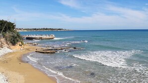 A coastal beach with a rocky shoreline, a pier, and a clear sky. - CASA SAURO 10 (Avola)