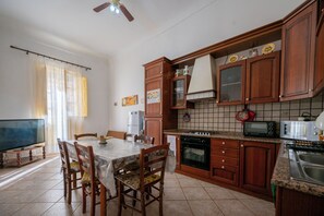 Eine Küche mit Holzausstattung, einem Esstisch mit Stühlen, einem Kühlschrank, einem Herd und einer Mikrowelle.